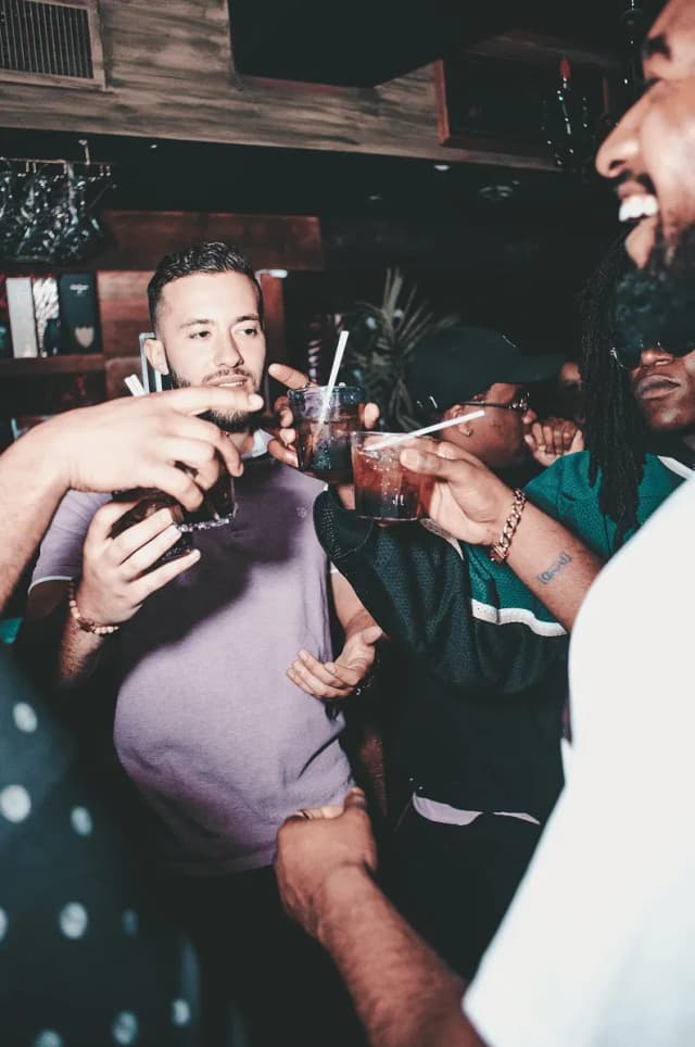 Group of men in a bar raising glasses for a toast while socializing.