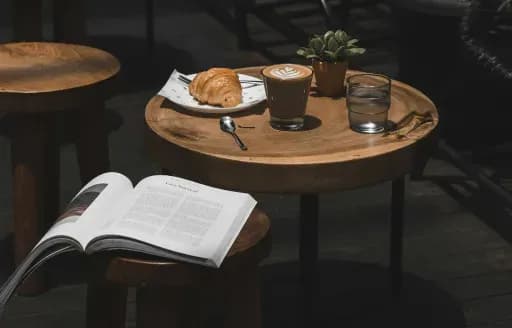 Coffee, croissant, and magazine on table
