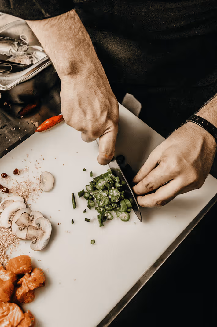 Hands chopping green onions on a cutting board